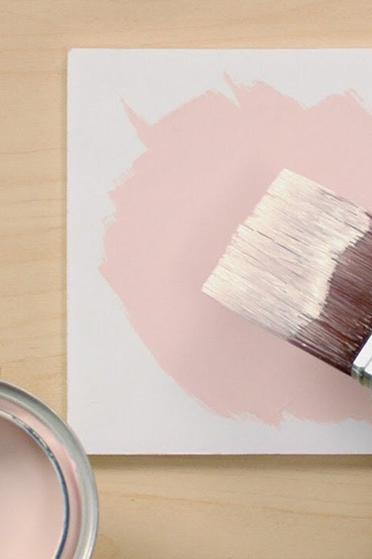 top down view of paint brush paint can and white block with pink circle painted on